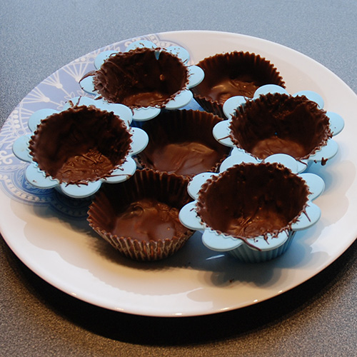 Suksessmakroner (etter oppskrift fra Baker Brun) Ingredienser: Topping: 200 g Kokesjokolade 15 Muffinsformer Suksesskrem: 1 dl Kremfløte 125 g Sukker 4 Eggeplommer 1 Vaniljestang (2 ts vaniljesukker) 150 g Smør (ekte) Mandelbunn: 500 g Mandler 500 g Sukker 7 Eggehviter