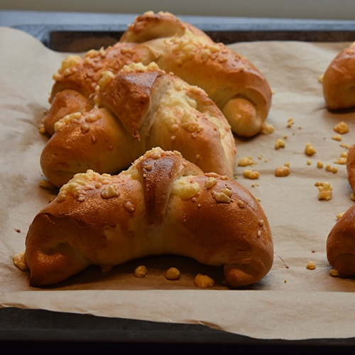 Ostehorn etter oppskrift fra baker brun Ingredienser: 13 dl Hvetemel 1 pk Gjær 2 ss Sukker 1 ts Salt 65 g Margarin 2½ dl Melk 3 dl Vann Egg (sammenvispet) Hvit ost (revet)