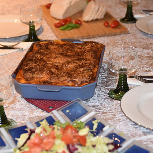 Lasagne al forno Ingredienser: Kjøttsaus: 2 ss Oliven olje 1 Løk 1 Gulrot 1 stilk Stangselleri 1 fedd Hvitløk ½ Chili (rød – uten frø) eller (kajennepepper) 350 g Kjøttdeig 50 g Bacon (kan sløyfes) 2 bx Hermetiske tomater 1 dl Vann (eller hvitvin) 1-2 Buljongterninger ½ - 1 ts Sukker Bladpersille (hakket) Salt og Pepper Ostesaus: 4 ss Hvetemel 8 dl Melk 1 ts Salt ½ ts Pepper 100-200 g Ost (revet)