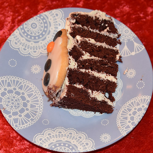 Snømannkake Ingredienser: 450 g Hvetemel (7 ½ dl) 400 g Sukker (5 dl) 4 ss Maisenna (70 g) 4-5 ss Kakao (70 g) 1 ss Natron 1 ts Bakepulver 4 Egg 3 dl Rømme 3 ½ dl Vann (varmt) 1 dl Olje (nøytral) 1 ts Vaniljeekstrakt 1 ts Eddik (eplesider) 2 ss Konditorfarge (rød) Fyll og topping: 500 g Kremost (Philadelphia) 225 g Smør 600 g Melis 1 ts Vaniljeekstrakt Pynt: Marsipansnømann Snømannkjeks