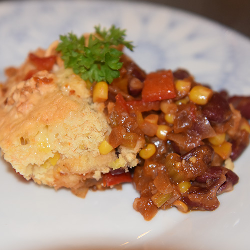 Mexicansk inspirert pai, med bønner, paprika og mais Ingredienser: 2 ss Margarin 2 fedd Hvitløk 1 Rødløk 2 stilker Stangselleri 2 Paprikaer (rød og gul) 1 ts Paprikapulver 1 ts Koriander ¼- ½ ts Kajennepepper Ca. 250 g Bønner (kokte) eller en boks hermetiske 225 g Mais (avrente) 1 bx Tomater (hermetiske, knuste) Salt, Pepper Maislokk: 125 g Maismel 1 ss Hvetemel 2 ts Bakepulver ½ ts Salt 1 Egg (pisket) 6 ss Melk 1 ss Olje (nøytral) 125 g Ost (revet)