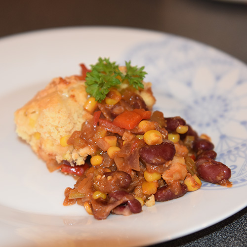 Mexicansk inspirert pai, med bønner, paprika og mais Ingredienser: 2 ss Margarin 2 fedd Hvitløk 1 Rødløk 2 stilker Stangselleri 2 Paprikaer (rød og gul) 1 ts Paprikapulver 1 ts Koriander ¼- ½ ts Kajennepepper Ca. 250 g Bønner (kokte) eller en boks hermetiske 225 g Mais (avrente) 1 bx Tomater (hermetiske, knuste) Salt, Pepper Maislokk: 125 g Maismel 1 ss Hvetemel 2 ts Bakepulver ½ ts Salt 1 Egg (pisket) 6 ss Melk 1 ss Olje (nøytral) 125 g Ost (revet)