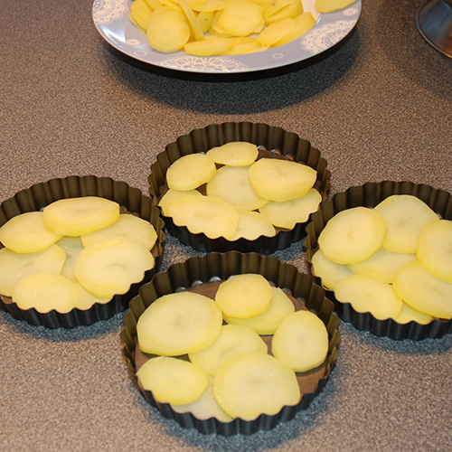 Squash – og tomatpai Ingredienser: 4 Poteter 1 Squash 1 Løk 1 Paprika (grønn) ¼ Purre (ca. 50 g) 1 fedd Hvitløk 1 ts Spisskumen 1 ts Paprikapuver 2 ss Basilikum (hakket) 1 ts Persile (hakket) 1 bx Tomater (hermetiske) 1 Mozzarella Salt og pepper 60 g Strøbrød 2 ss Parmesan 4 Terteformer (små, med løs bunn) Eller noe annet å steke dem i