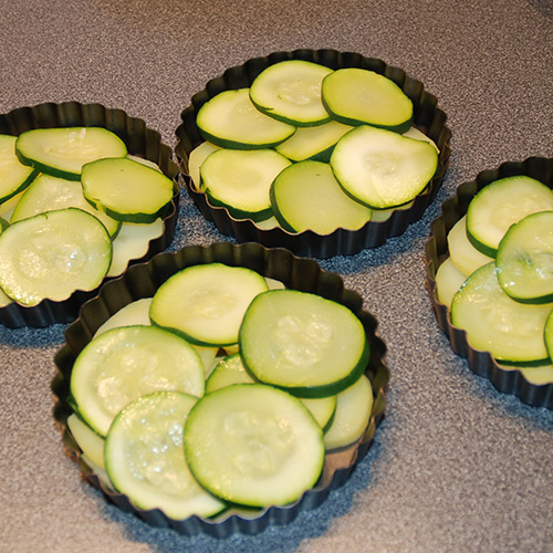 Squash – og tomatpai Ingredienser: 4 Poteter 1 Squash 1 Løk 1 Paprika (grønn) ¼ Purre (ca. 50 g) 1 fedd Hvitløk 1 ts Spisskumen 1 ts Paprikapuver 2 ss Basilikum (hakket) 1 ts Persile (hakket) 1 bx Tomater (hermetiske) 1 Mozzarella Salt og pepper 60 g Strøbrød 2 ss Parmesan 4 Terteformer (små, med løs bunn) Eller noe annet å steke dem i