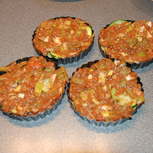 Squash – og tomatpai Ingredienser: 4 Poteter 1 Squash 1 Løk 1 Paprika (grønn) ¼ Purre (ca. 50 g) 1 fedd Hvitløk 1 ts Spisskumen 1 ts Paprikapuver 2 ss Basilikum (hakket) 1 ts Persile (hakket) 1 bx Tomater (hermetiske) 1 Mozzarella Salt og pepper 60 g Strøbrød 2 ss Parmesan 4 Terteformer (små, med løs bunn) Eller noe annet å steke dem i