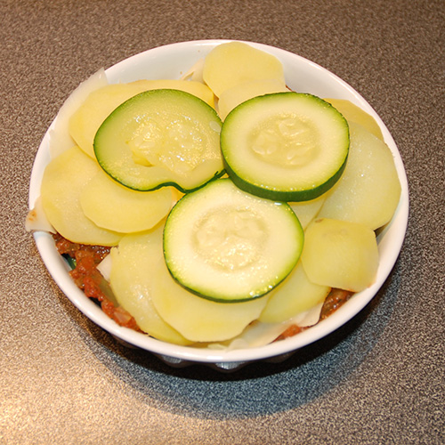 Squash – og tomatpai Ingredienser: 4 Poteter 1 Squash 1 Løk 1 Paprika (grønn) ¼ Purre (ca. 50 g) 1 fedd Hvitløk 1 ts Spisskumen 1 ts Paprikapuver 2 ss Basilikum (hakket) 1 ts Persile (hakket) 1 bx Tomater (hermetiske) 1 Mozzarella Salt og pepper 60 g Strøbrød 2 ss Parmesan 4 Terteformer (små, med løs bunn) Eller noe annet å steke dem i