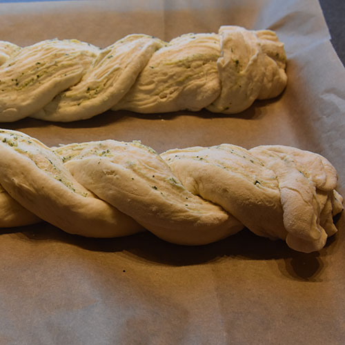 Flettet hvitløk- og basilikumbrød Ingredienser: 1 pk Gjær ½ dl Vann (fingervarmt) ½ ts Sukker 600 g Hvetemel ½ ts Salt 50 g Smør 4 dl Melk (skummet/lett) Fyll og topping: 100 g Smør (mykt) ½ bunt Basilikum (fersk) 4 fedd Hvitløk 1 Egg (sammenpisket)