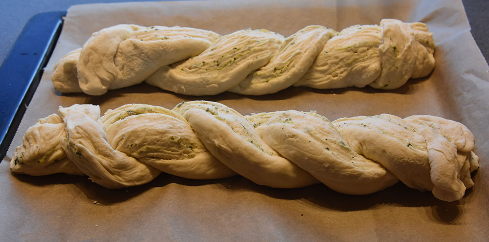 Flettet hvitløk- og basilikumbrød Ingredienser: 1 pk Gjær ½ dl Vann (fingervarmt) ½ ts Sukker 600 g Hvetemel ½ ts Salt 50 g Smør 4 dl Melk (skummet/lett) Fyll og topping: 100 g Smør (mykt) ½ bunt Basilikum (fersk) 4 fedd Hvitløk 1 Egg (sammenpisket)