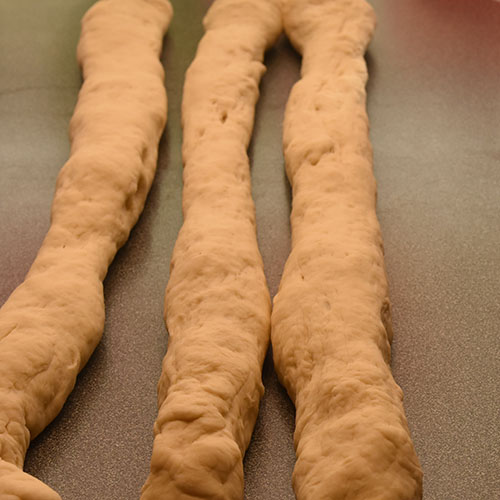 Hvetebrød i dobbel flette Ingredienser: 1 ts Salt 2 ss Olje 5 dl Vann (fingervarmt) 1 pk Gjær 2 Egg 1 ss Sukker Ca. 13 dl Hvetemel Egg (pisket), valmuefrø