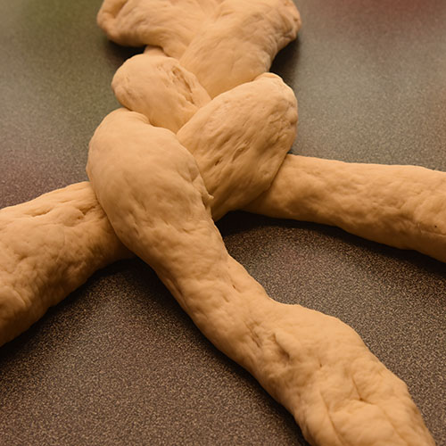 Hvetebrød i dobbel flette Ingredienser: 1 ts Salt 2 ss Olje 5 dl Vann (fingervarmt) 1 pk Gjær 2 Egg 1 ss Sukker Ca. 13 dl Hvetemel Egg (pisket), valmuefrø