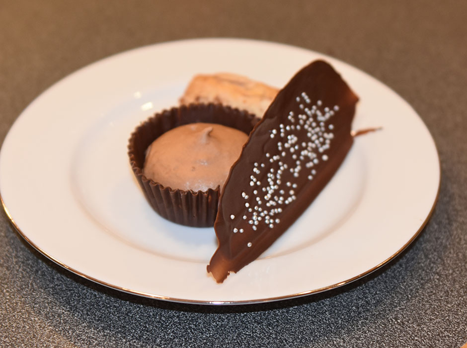 Sjokolademoussé med mandelstang, pyntet med sjokolade og sølvkuler Ingredienser: Sjokoladeskåler, og pynt: 200 g Kokesjokolade 15 Muffinsformer Kakestrø - glitter Sjokolademousse: 3 plater Gelatin 150 g Kokesjokolade 4 ss Kaffe (sterk) 3 ss Sukker 2 Egg (delte) 3 dl Kremfløte Mandelstang: 500 g Mandler (malte) 500 g melis 3-4 Eggehviter Kokesjokolade Mandelflak