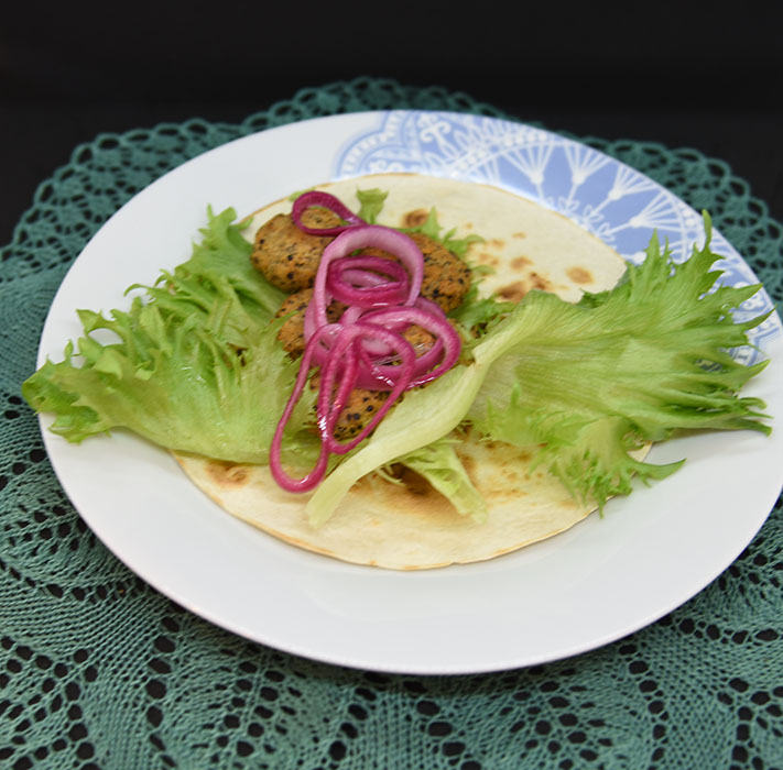 Ingredienser: 50 g Quinoa 1 dl Grønsakskraft (eller -buljong) 400 g Bønner (hvite) 1 Sjalottløk ½ ts Kajennepepper 1 ts Paprikapulver 1 ss Oregano (tørket) 1 ts Koriander (malt) 1 ss Ketchup 30 g Brødrasp 1 Egg Salt, pepper Olje 6 Tortillalefser Salat Syltet rødløk: 1 Rødløk 1 dl Vann ½ dl Eddik (7%) 1 dl Sukker Chilimajones: 2 dl Majones 1 ss Rømme 2 ts Sursøt-chilisaus 1 ts Sitronsaft Salt og pepper