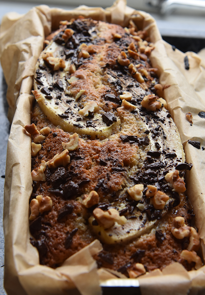 KRISTINS BANANBRØD Ingredienser: 2 ½ dl Hvetemel 2 ts Bakepulver 1 ts Vaniljesukker 1 ts Kardemomme (valgfritt) 2 Egg 1 ½ dl Sukker 50 g Smør 1 dl Melk 40 g Kokesjokolade (mørk, hakket) 40 g Valnøtter 2 Bananer (godt modne, gjerne med brune flekker) Topping: 10 g Kokesjokolade (mørk, hakket) 10 g Valnøtter 1 Banan