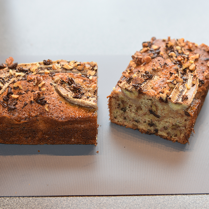 KRISTINS BANANBRØD Ingredienser: 2 ½ dl Hvetemel 2 ts Bakepulver 1 ts Vaniljesukker 1 ts Kardemomme (valgfritt) 2 Egg 1 ½ dl Sukker 50 g Smør 1 dl Melk 40 g Kokesjokolade (mørk, hakket) 40 g Valnøtter 2 Bananer (godt modne, gjerne med brune flekker) Topping: 10 g Kokesjokolade (mørk, hakket) 10 g Valnøtter 1 Banan