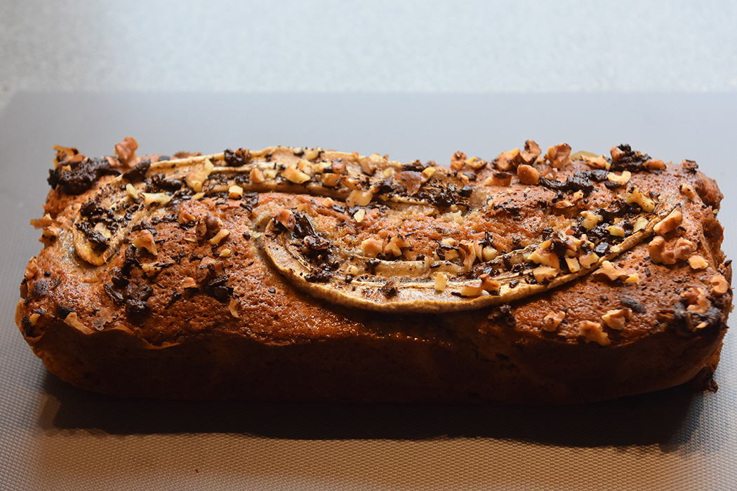 KRISTINS BANANBRØD Ingredienser: 2 ½ dl Hvetemel 2 ts Bakepulver 1 ts Vaniljesukker 1 ts Kardemomme (valgfritt) 2 Egg 1 ½ dl Sukker 50 g Smør 1 dl Melk 40 g Kokesjokolade (mørk, hakket) 40 g Valnøtter 2 Bananer (godt modne, gjerne med brune flekker) Topping: 10 g Kokesjokolade (mørk, hakket) 10 g Valnøtter 1 Banan