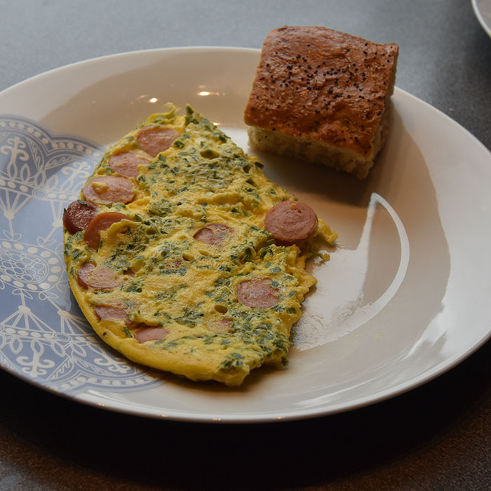 Pølseomelett Ingredienser: ½ - 1 ss Smør 3 Egg 3 ss Melk (eller vann) 2 Grillpølser 1 ss Gressløk (hakket) - valgfritt 1 ss Persille (hakket) - valgfritt Salt og pepper