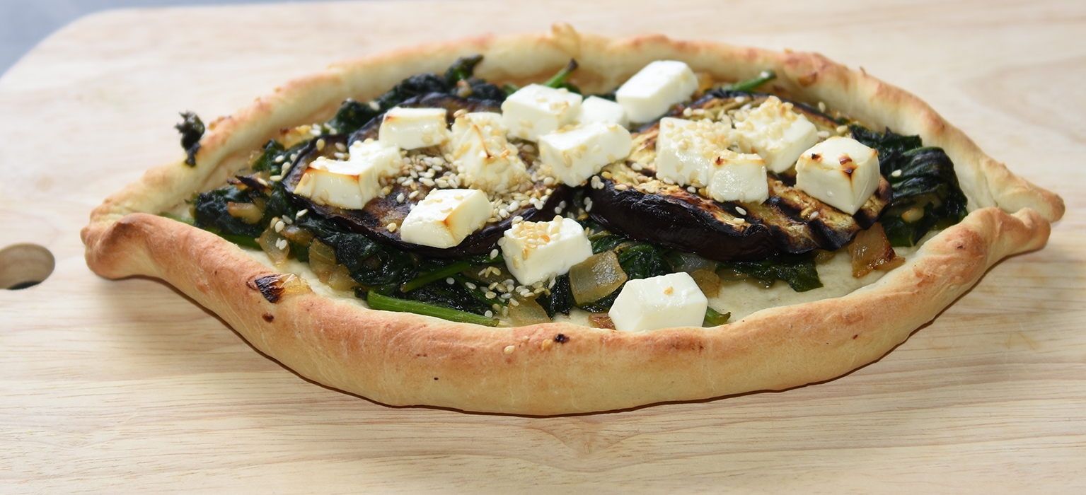 Ingredienser:  Bunn:  ½ pk	Gjær 1 ts	Sukker 300 g	Hvetemel 2 ts	Salt 2 ss	Olje (oliven) ca. 1 ½ dl	Vann (fingervarmt)  Topping: 1	Aubergine (skivet) 1 	Løk (skivet) 2 fedd	Hvitløk 1 pk	Babyspinat 150 g	Fetaost 1 ss	Sesamfrø