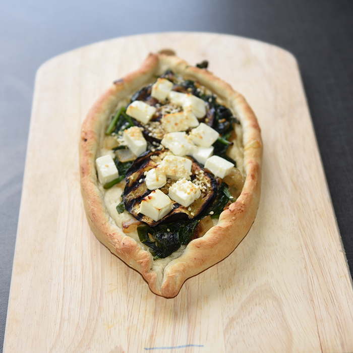 Ingredienser:  Bunn:  ½ pk	Gjær 1 ts	Sukker 300 g	Hvetemel 2 ts	Salt 2 ss	Olje (oliven) ca. 1 ½ dl	Vann (fingervarmt)  Topping: 1	Aubergine (skivet) 1 	Løk (skivet) 2 fedd	Hvitløk 1 pk	Babyspinat 150 g	Fetaost 1 ss	Sesamfrø