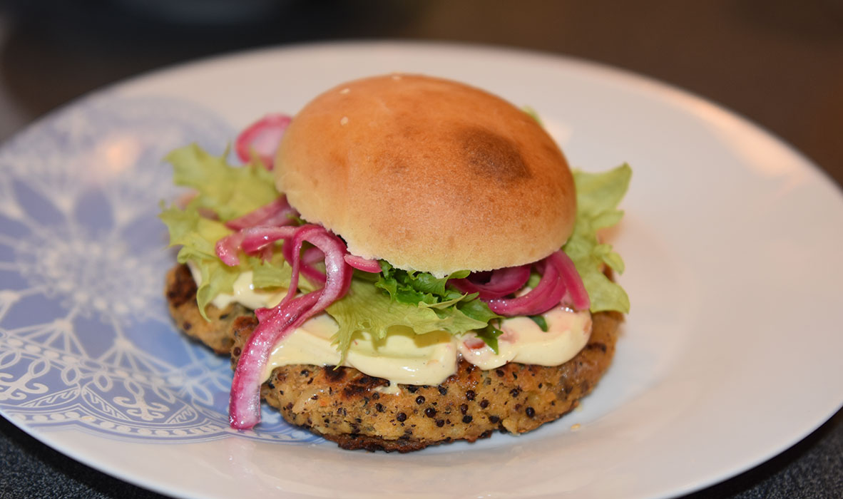 Quinoaburger Ingredienser: 50 g Quinoa 1 dl Grønsakskraft (eller -buljong) 400 g Bønner (hvite) 1 Sjalottløk ½ ts Kajennepepper 1 ts Paprikapulver 1 ss Oregano (tørket) 1 ts Koriander (malt) 1 ss Ketchup 30 g Brødrasp 1 Egg Salt, pepper Olje 4 Hamburgerbrød Salat