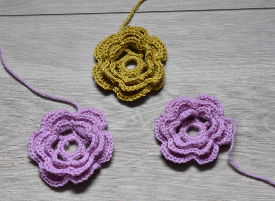 Heklet Rose Sik gjør du (Roser): Tvinn tråden 3-4 ganger rundt en finger og sett sammen med en kjedemaske (kjm) Omgang 1: 1 luftmaske (lm), 17 fastmasker i ringen, avslutt med 1 kjm i den 1. lm Omgang 2: 6 lm Hopp over 2 fm 1 halvstav (hst) i neste fm *4 lm Hopp over 2 fm, 1 hst i neste fm* GJENTA fra * til * 3 ganger til 4 lm Avslutt med 1 kjm 1 den 2. lm (på begynnelsen av omgangen) Omgang 3: I hver av de lm-buene hekles det: 1 fm, 1 hst, 3 st, 1 ht, 1 fm Avslutt med 1 kjm 1 den 1. lm (på begynnelsen av omgangen) Omgang 4: 1 kjm i bakre del av hst fra omg nr.2 *5 lm Hold garnet på baksiden av blomsten 1 kjm i neste Hst fra omg nr 2 * GJENTA fra * til * 4 ganger til 5 lm Avslutt med 1 kjm i den samme hst som i begynnelsen av omg Omgang 5: I hver av lm-buene hekles det: 1 fm, 1 hst, 5 st, 1 ht, 1 fm Avslutt med 1 kjm 1 den 1. lm (på begynnelsen av omgangen) Omgang 6: 1 kjm i bakre del av hst fra omg nr.4 *5 lm Hold garnet på baksiden av blomsten 1 kjm i neste Hst fra omg nr 4 * GJENTA fra * til * 4 ganger til 5 lm Avslutt med 1 kjm i den samme hst som i begynnelsen av omg Omgang 7: I hver av lm-buene hekles det: 1 fm, 1 hst, 7 st, 1 ht, 1 fm Avslutt med 1 kjm 1 den 1. lm (på begynnelsen av omgangen)