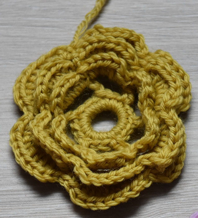 Heklet Rose Sik gjør du (Roser): Tvinn tråden 3-4 ganger rundt en finger og sett sammen med en kjedemaske (kjm) Omgang 1: 1 luftmaske (lm), 17 fastmasker i ringen, avslutt med 1 kjm i den 1. lm Omgang 2: 6 lm Hopp over 2 fm 1 halvstav (hst) i neste fm *4 lm Hopp over 2 fm, 1 hst i neste fm* GJENTA fra * til * 3 ganger til 4 lm Avslutt med 1 kjm 1 den 2. lm (på begynnelsen av omgangen) Omgang 3: I hver av de lm-buene hekles det: 1 fm, 1 hst, 3 st, 1 ht, 1 fm Avslutt med 1 kjm 1 den 1. lm (på begynnelsen av omgangen) Omgang 4: 1 kjm i bakre del av hst fra omg nr.2 *5 lm Hold garnet på baksiden av blomsten 1 kjm i neste Hst fra omg nr 2 * GJENTA fra * til * 4 ganger til 5 lm Avslutt med 1 kjm i den samme hst som i begynnelsen av omg Omgang 5: I hver av lm-buene hekles det: 1 fm, 1 hst, 5 st, 1 ht, 1 fm Avslutt med 1 kjm 1 den 1. lm (på begynnelsen av omgangen) Omgang 6: 1 kjm i bakre del av hst fra omg nr.4 *5 lm Hold garnet på baksiden av blomsten 1 kjm i neste Hst fra omg nr 4 * GJENTA fra * til * 4 ganger til 5 lm Avslutt med 1 kjm i den samme hst som i begynnelsen av omg Omgang 7: I hver av lm-buene hekles det: 1 fm, 1 hst, 7 st, 1 ht, 1 fm Avslutt med 1 kjm 1 den 1. lm (på begynnelsen av omgangen)