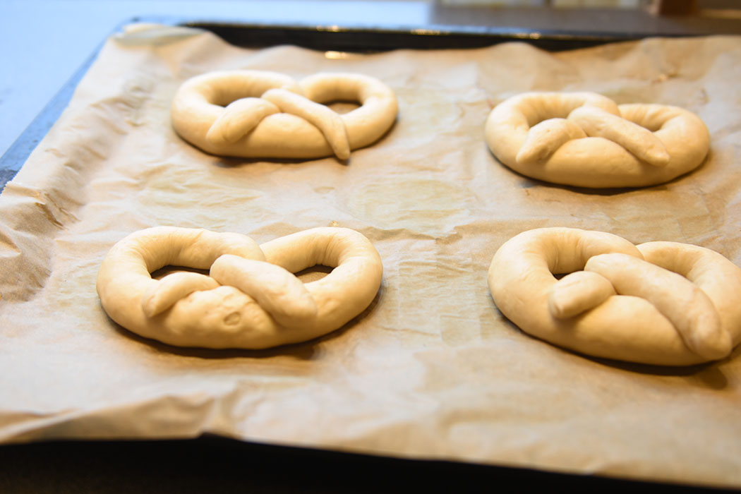 Pretzel (myke) Ingredienser: 2 ½ ts Tørrgjær 1 ¼ dl Vann (varmt ca. 38-45 grader) 1 ss Sirup (mørk) 450 g Hvetemel 1,2 dl Øl (pilsner) 2 ss Smør (romtemperert) 2 ts Salt 0,6 dl Natron 1 Eggeplomme 1 ss Vann (kaldt) Salt (flak eller korn)