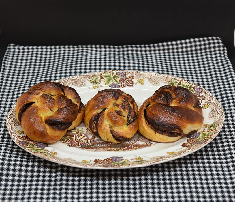 Sjokoladeknuter Ingredienser: 6 dl Melk 1 pk Gjær 1 kg Hvetemel 150 g Sukker 3 ts Flaksalt 3 ts Kardemomme 1 Egg 150 g Smør