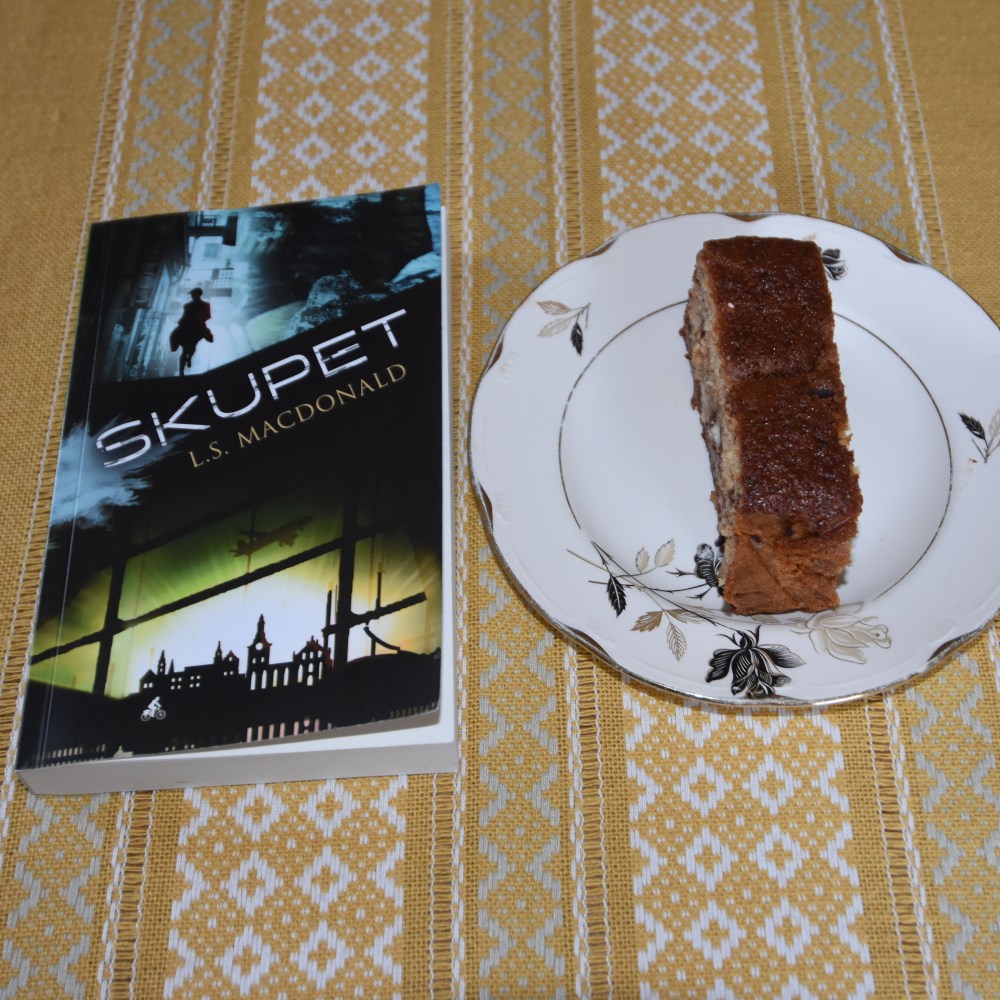 LS Macdonald (2021) «Skupet», Macademics Forlag OG KRISTINS BANANBRØD Ingredienser: 2 ½ dl Hvetemel 2 ts Bakepulver 1 ts Vaniljesukker 1 ts Kardemomme (valgfritt) 2 Egg 1 ½ dl Sukker 50 g Smør 1 dl Melk 40 g Kokesjokolade (mørk, hakket) 40 g Valnøtter 2 Bananer (godt modne, gjerne med brune flekker) Topping: 10 g Kokesjokolade (mørk, hakket) 10 g Valnøtter 1 Banan https://heidisboble.no/ @heidisboble