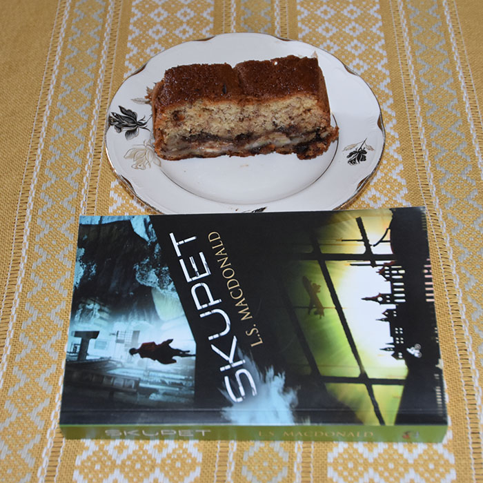 LS Macdonald (2021) «Skupet», Macademics Forlag OG KRISTINS BANANBRØD Ingredienser: 2 ½ dl Hvetemel 2 ts Bakepulver 1 ts Vaniljesukker 1 ts Kardemomme (valgfritt) 2 Egg 1 ½ dl Sukker 50 g Smør 1 dl Melk 40 g Kokesjokolade (mørk, hakket) 40 g Valnøtter 2 Bananer (godt modne, gjerne med brune flekker) Topping: 10 g Kokesjokolade (mørk, hakket) 10 g Valnøtter 1 Banan https://heidisboble.no/ @heidisboble